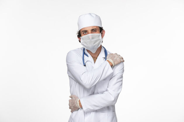 前面正面图男医生穿着医用西服 戴着无菌口罩作为防护罩 免受冠状病毒在白墙上溅起的冠状病毒大流行的危害消毒防护冠状病毒