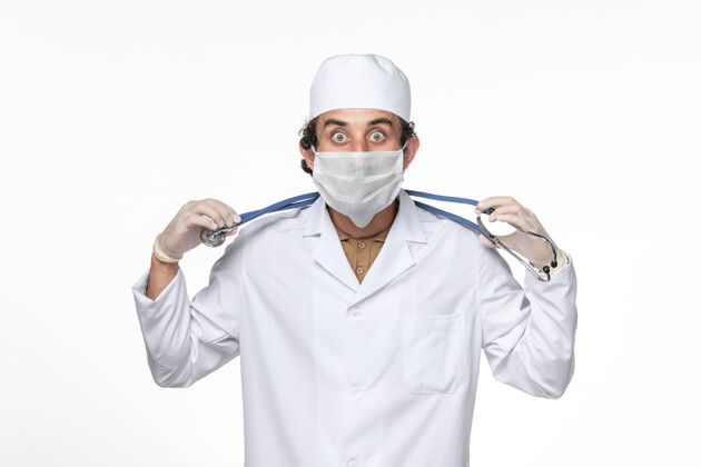 视图正面图：男医生穿着医疗服 戴着口罩 以防白墙冠状病毒大流行防护医生专业