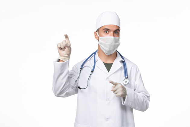医生正面图：男医生穿着医疗服 戴着口罩 对抗白色壁上的冠状病毒病医学大流行病毒男士男性外套