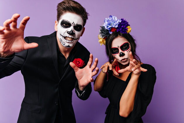 女人可爱的女孩与男友在万圣节化妆吓人无忧无虑的情侣穿着吸血鬼服装在派对上玩的室内照片传统僵尸西班牙