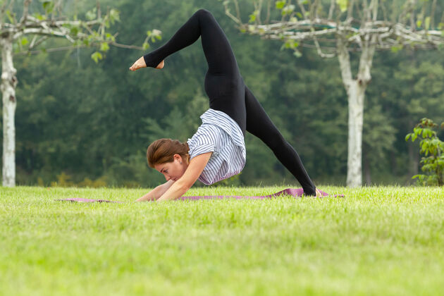 平衡年轻漂亮的女人在绿色公园做瑜伽练习私人教练快乐饮食