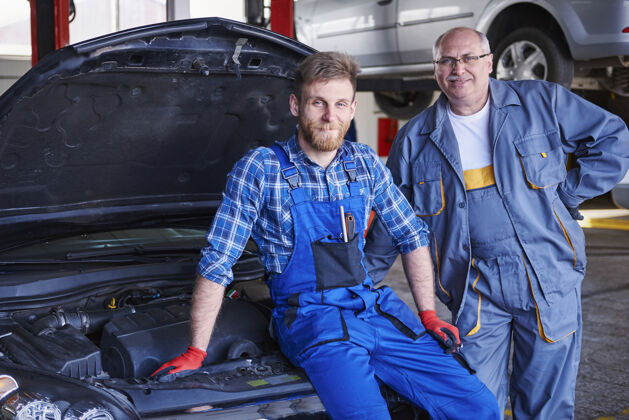 设备修理工在车间里修理汽车室内机械师微笑