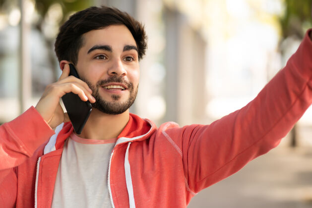 手机一幅年轻人在街上打电话举手招呼出租车的照片城市概念设备户外无线