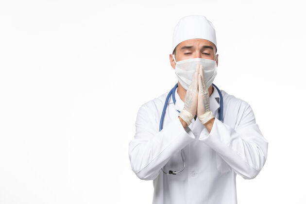 冠状病毒预防正面图：男医生穿着医疗服 戴着口罩 因为白色办公桌上有冠状病毒-病毒大流行病毒疾病正面实验室外套成人