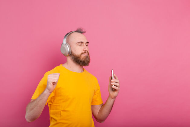 背景帅哥带着手机和耳机在粉色背景上翩翩起舞音频年轻手势