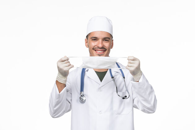 医生正面图男医生身着医疗服 戴着防冠状病毒口罩微笑着对着白墙病毒-疾病大流行专业大流行西装