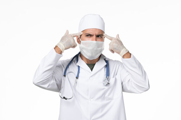 疾病正面图：男医生穿着医疗服 戴着口罩 因为柯维德-思考白墙柯维德-大流行病毒疾病外套冠状病毒病毒