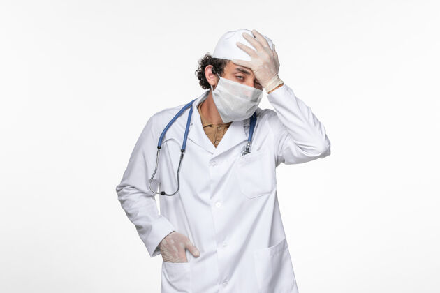 正面正面图男医生穿着医疗服 戴着无菌口罩 以防柯维德强调白壁病毒引起的冠状病毒大流行疾病穿着压力冠状病毒