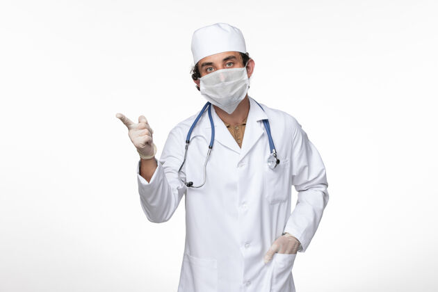 实验室外套正面图：男医生穿着医疗服 戴着无菌口罩 以防柯维德病毒在白墙病毒疾病上冒充柯维德大流行疾病疾病医生姿势