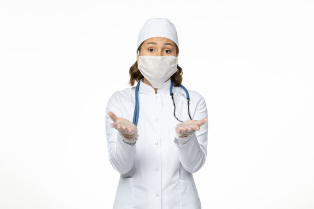 病毒正面图女医生穿着白色医疗服 戴着口罩 因白墙上有冠状病毒病大流行性冠状病毒套装冠状病毒正面
