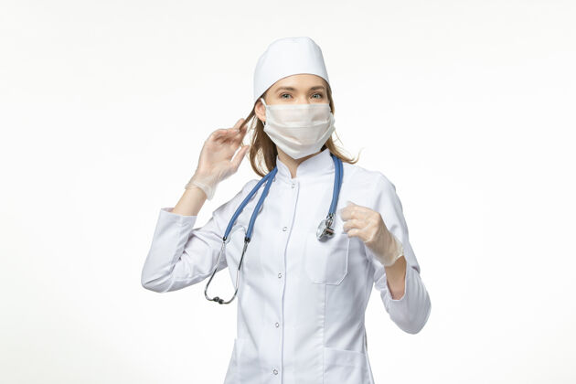 女性正面图女医生身穿医疗服戴口罩因白墙上冠状病毒大流行病毒冠状病毒-疾病医生套装医疗