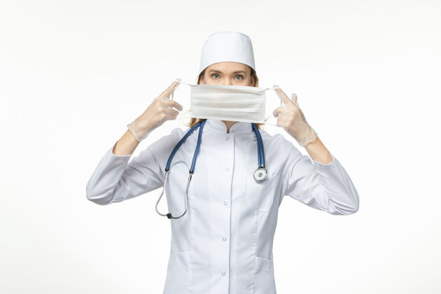 冠状病毒预防正面图女医生身穿医疗服戴口罩因白色办公桌上冠状病毒大流行病毒冠状病毒-疾病人员西装帽子