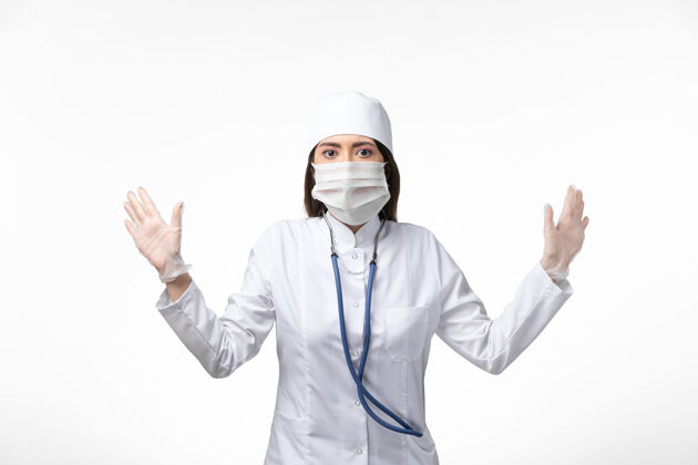 视图正面图：女医生穿着白色无菌医疗服 戴着口罩 因为白墙疾病 病毒大流行女性大流行到期