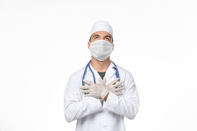 男性正面图：男医生穿着医疗服 戴着防毒面具 在白色墙壁上大流行病毒药正面视图病毒