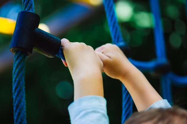 孩子低角度拍摄的一个孩子抱着一个蓝色的攀岩玩具在操场上的公园乐趣女孩童年