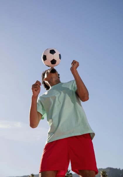 男一个正在踢足球的年轻人体育头球球员