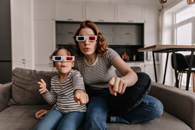 女人惊喜的母女俩戴着3d眼镜坐在沙发上看电影拥抱快乐快乐