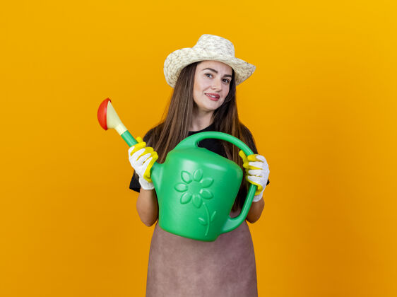 花园微笑美丽的园丁女孩穿着制服 戴着园艺帽 戴着手套 手里拿着浇水罐微笑手套漂亮