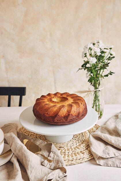 花瓶美丽的镜头美味的环蛋糕放在一个白色的盘子和一个白色的花靠近它桌子传统面包房