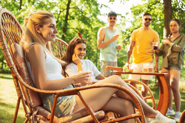干杯一群快乐的朋友在阳光明媚的日子里喝着啤酒 一起烧烤一起在户外的林间空地或后院休息自然饮料烹饪