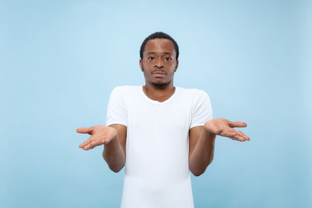 一半半身特写肖像的年轻非洲裔美国男模在白衬衫蓝色空间人类的情感 面部表情 广告概念专业就业男人