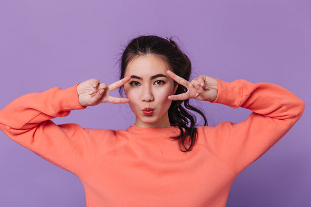 兴奋展现和平标志的性感亚洲女人的正面图在紫色背景上有吸引力的日本女人的摄影棚拍摄肖像紫色背景中国人