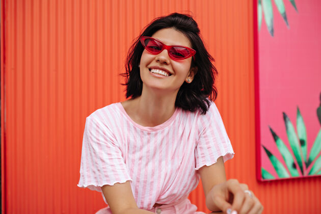人穿着条纹t恤的兴奋女人的正面图戴着粉色太阳镜的笑着晒黑的女人的户外照片欧洲街道时尚