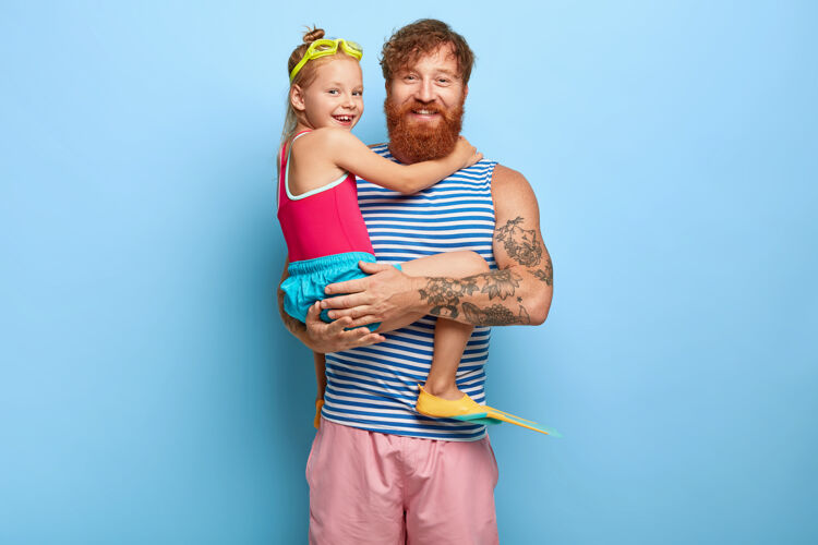 家庭工作室拍摄了高兴的姜爸爸和女儿在游泳池服装摆姿势童年小爸爸