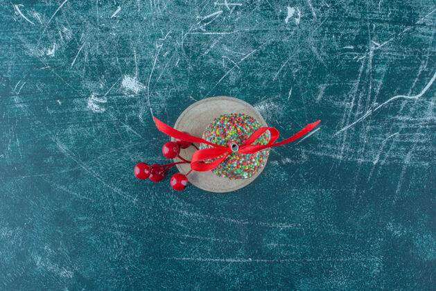 美味一个圣诞浆果装饰品和一个棒棒糖在一块木头上的蓝色背景高品质的照片糖装饰品浆果