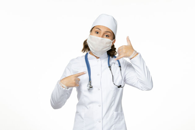 医疗正面图年轻女医生穿着白色的医疗服 由于白色表面有冠状病毒 戴着无菌口罩医生冠状病毒疾病