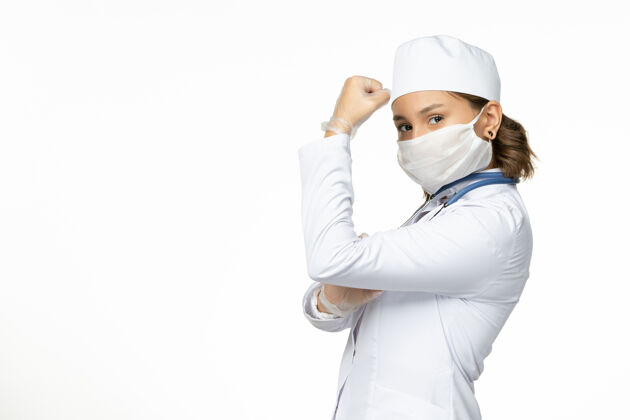 手套正面图年轻女医生戴着无菌口罩和手套 因为白色表面上有冠状病毒在与它战斗正面大流行绝育