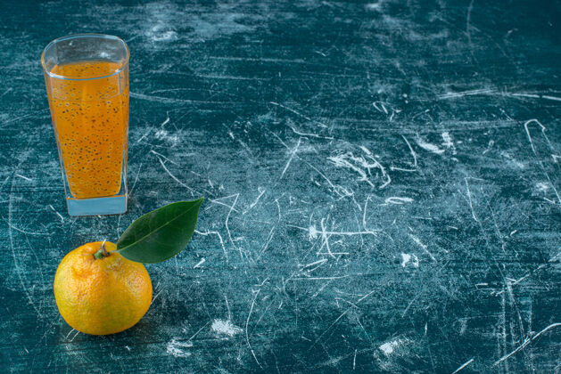 甜味橘子和一杯果汁在蓝色的背景上高质量的照片有机美味果汁