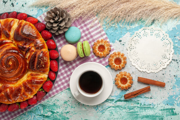 早餐俯瞰草莓派 配上饼干 法式马卡龙和蓝色表面的一杯茶食物马卡龙草莓