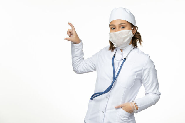 灭菌正面图年轻女医生戴防护无菌口罩因冠状病毒在浅白色表面疾病正面医生