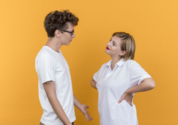 女人一对年轻的运动情侣站在橘色的墙上看着彼此争吵看争论男人