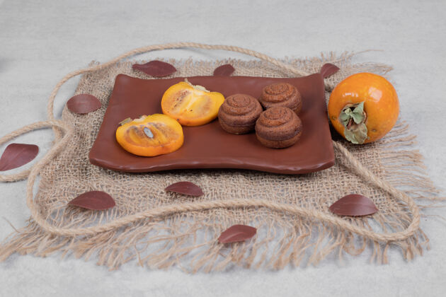 柿子巧克力饼干和柿子片放在盘子里高质量的照片粗麻布糕点水果