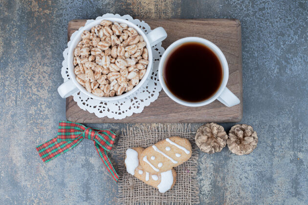 杯子两个圣诞饼干 一杯茶和甜花生放在木板上高质量的照片茶糕点节日