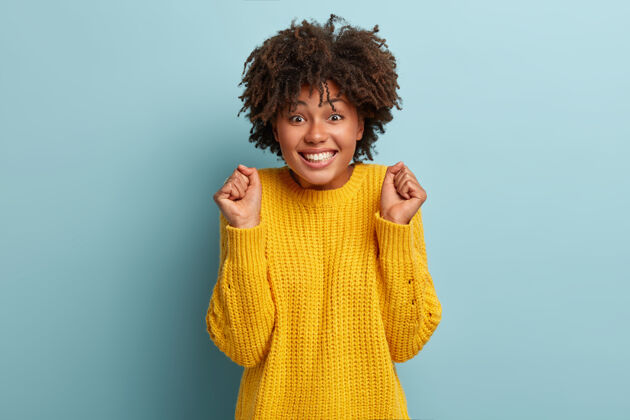 欢呼一个穿着粉色毛衣的非洲裔欢呼女人的肖像毛衣发型微笑