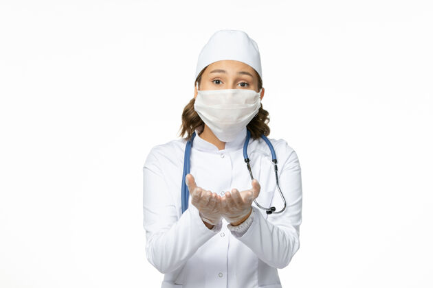 医生白色办公桌上戴着无菌口罩和手套的年轻女医生正面大流行冠状病毒