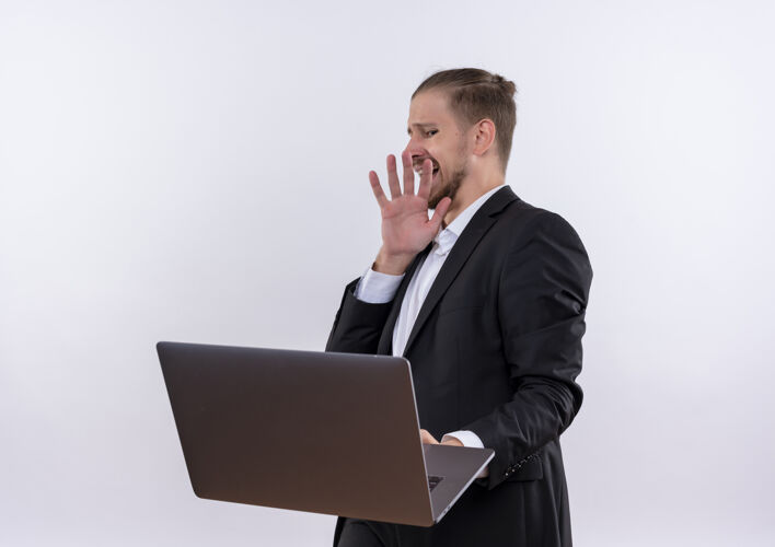 笔记本电脑穿着西装的帅哥拿着笔记本电脑站在白色背景上做着厌恶的防御手势制造穿着手势