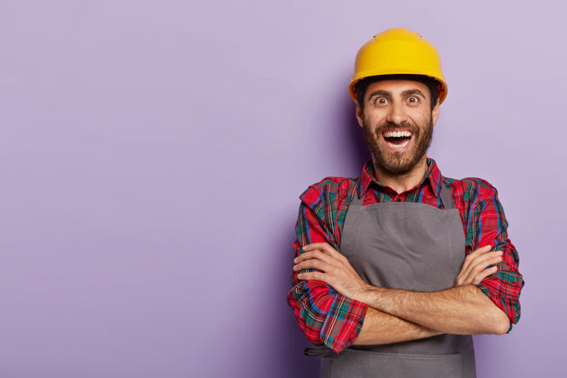 工人积极快乐的工头穿着工作服 双臂交叉 戴着黄色安全帽折叠工程师职业