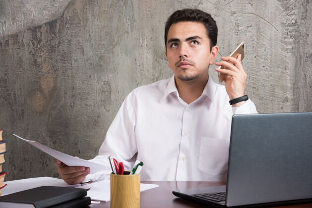 笔记本电脑认真的员工坐在办公桌旁听电话语音邮件高质量的照片男办公室人