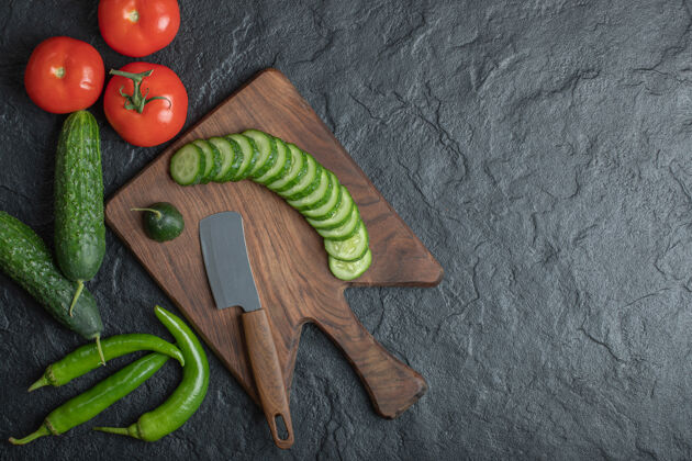 生的木板上的新鲜蔬菜西红柿黄瓜和青椒高品质照片生的刀一串