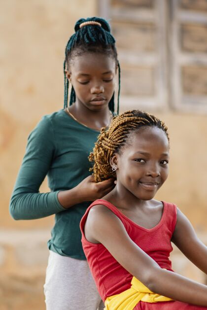 贫困中枪女孩编织朋友的头发户外孩子民族