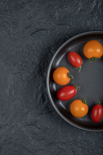 盘子半个彩色的樱桃番茄放在锅里 黑色背景高质量的照片传统乡村生的