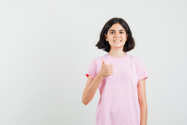 人小女孩在粉红色的t恤衫上竖起大拇指 看起来很高兴正视图美丽青少年肖像