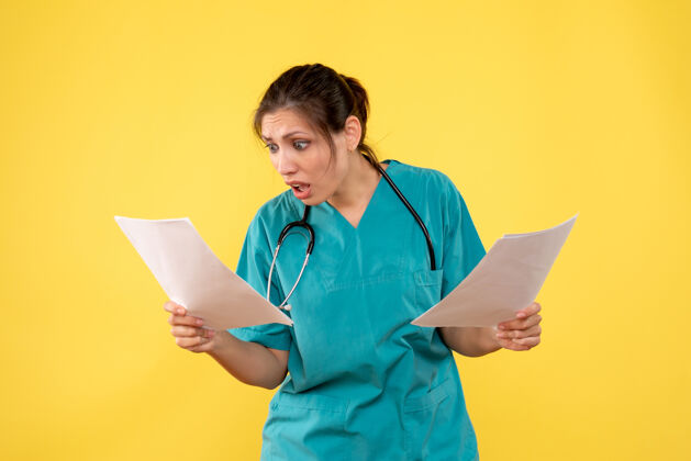 专业正面图年轻女医生穿着医用衬衫拿着黄色背景的纸张分析看医生前面