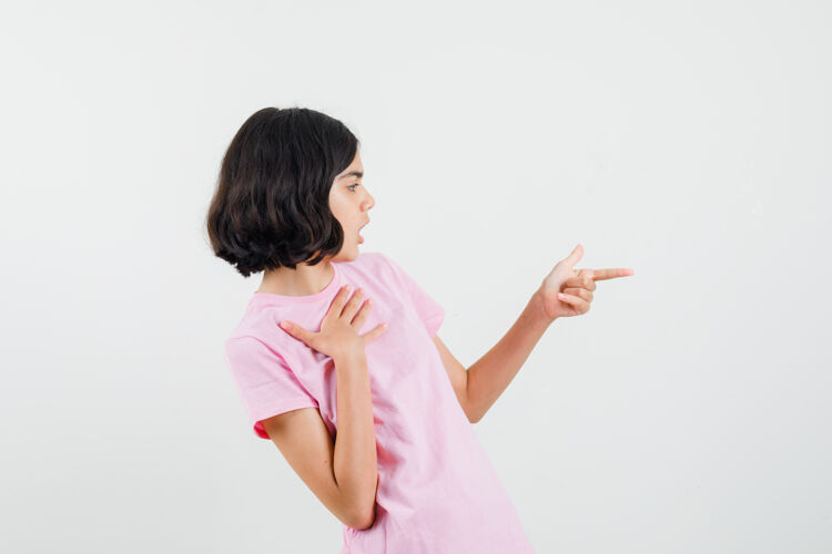 粉色小女孩做手指标志在粉红色t恤和寻找重点前视图看人