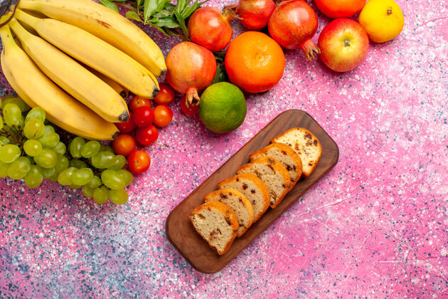 蔬菜顶视黄色新鲜香蕉美味的水果与葡萄蛋糕和石榴在粉红色的办公桌上生的维生素番茄