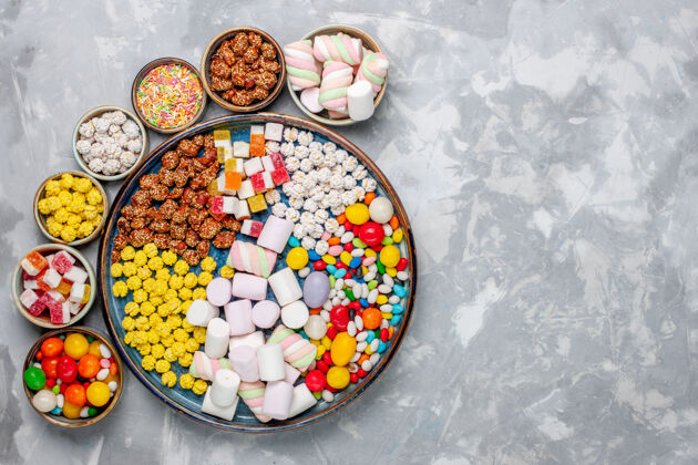颜色顶视图糖果组成不同颜色的糖果与棉花糖内锅在淡白色的办公桌糖糖果邦邦甜封盘子成分糖果